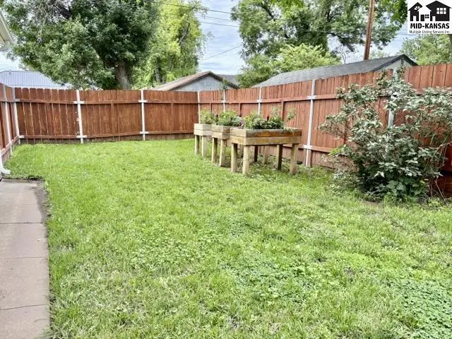 Spacious backyard with a wooden privacy fence and raised garden beds.