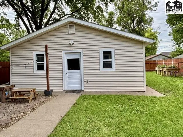 Exterior of a beige vinyl-sided home with white trim, a white door, and two windows.