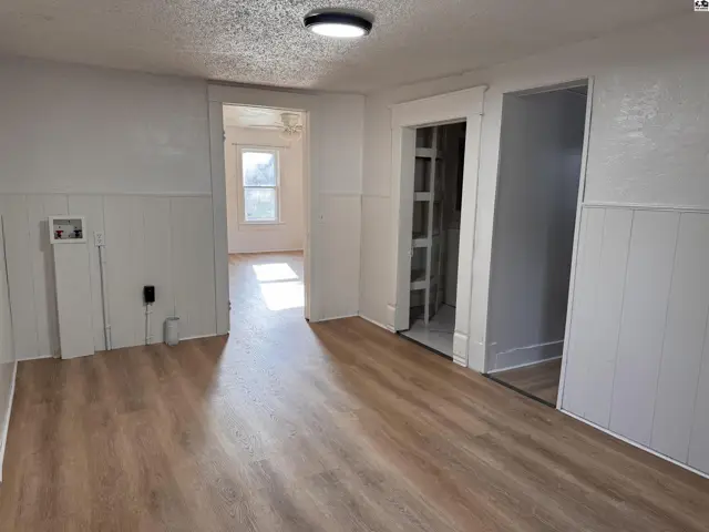 Living room with wood-look flooring, white wainscoting, and a view into another room.