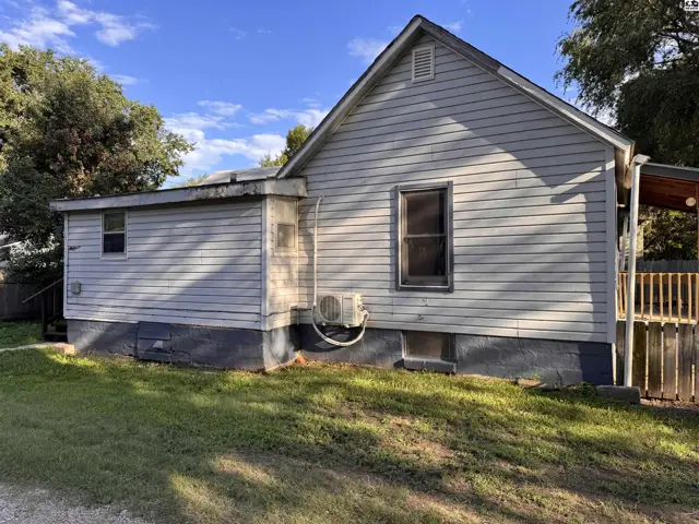 Exterior view of a light gray vinyl-sided house with a wooden deck and a covered porch.