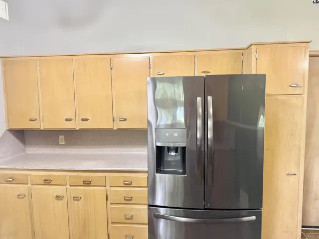 Kitchen with light wood cabinets, laminate countertops, and a stainless steel French door refrigerator.