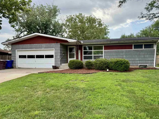 Ranch-style home with gray siding, red accents, and a white garage door.
