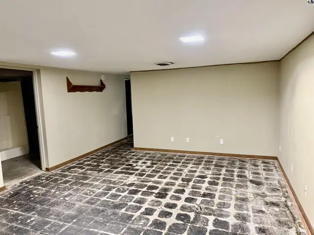 Spacious unfinished basement room with textured flooring, neutral walls, and recessed lighting.