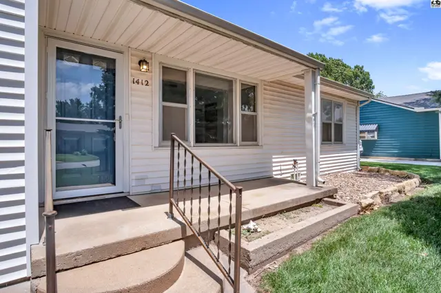 White vinyl siding and a covered porch with concrete steps lead to the front door.