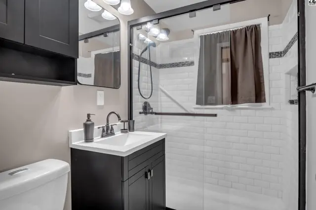 Modern bathroom with subway tile shower, dark vanity, and sleek fixtures.