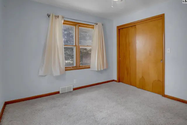 Light blue bedroom with a large closet, carpet, and a wood-trimmed window.