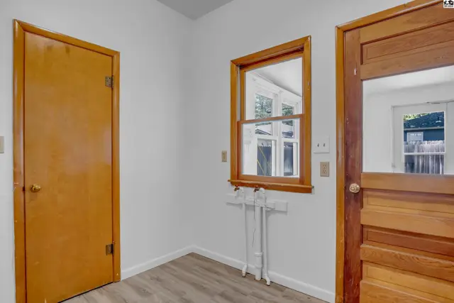 Interior view of a laundry room with wood doors, a window, and laminate flooring.
