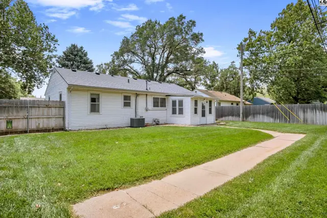 White vinyl-sided home with a fenced backyard and concrete walkway.
