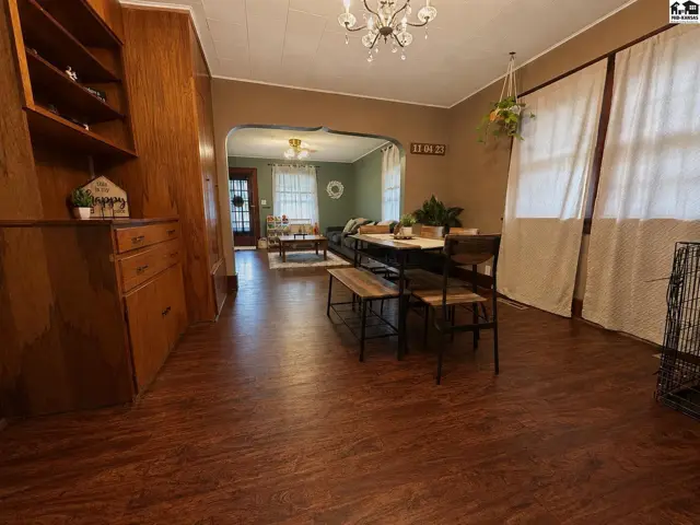 Dining area with wood paneling, a chandelier, and a view into a living room.