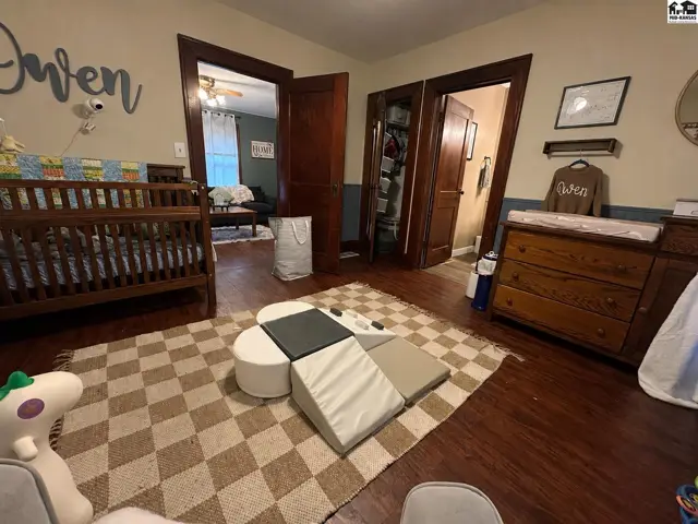 Nursery with wooden crib, changing dresser, and soft play mats on a checkered rug.