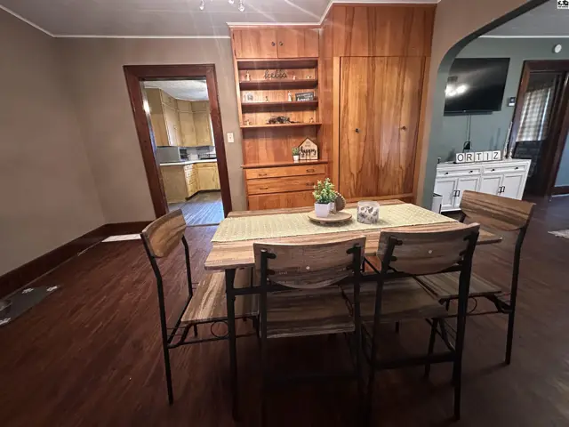 Dining area with wooden table and chairs, adjacent to a built-in wooden cabinet and doorway.