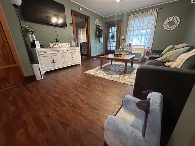 Cozy living room with dark sofa, wood floors, and a white media console.