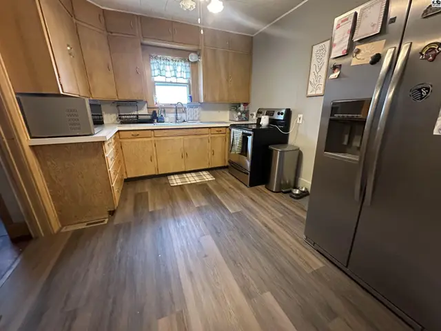 Kitchen with light wood cabinets, stainless steel appliances, and wood-look vinyl flooring.
