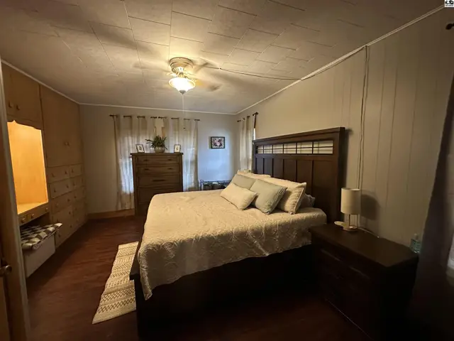 Spacious bedroom with a dark wood bed frame, white bedding, and built-in wood cabinetry.