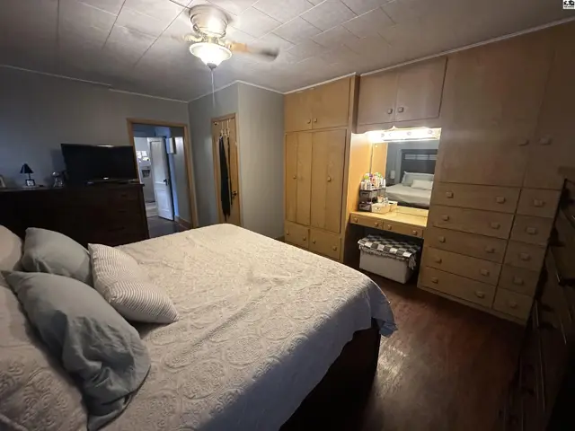 Spacious bedroom with a large bed, built-in wooden wardrobes, and a vanity area.