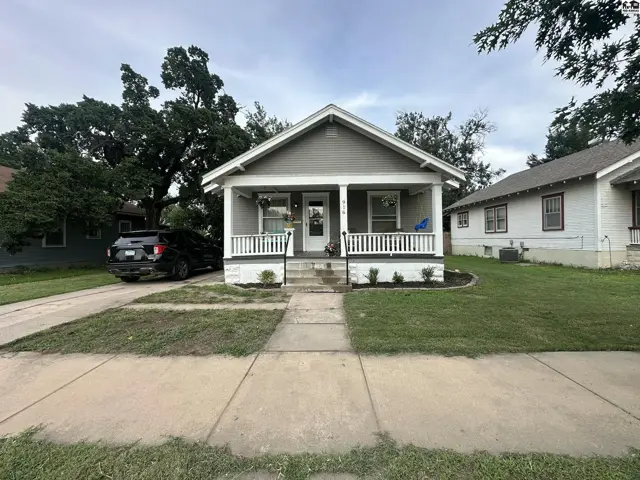 Charming gray bungalow with white trim, a covered front porch, and a paved driveway.