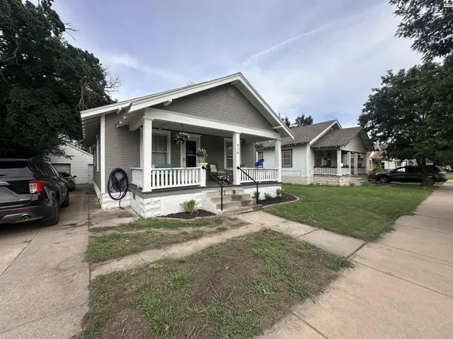 Charming gray bungalow with white trim, a covered porch, and a detached garage.