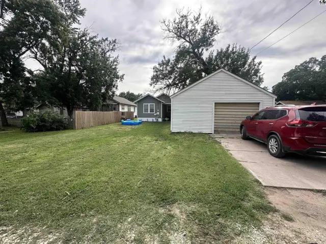 Exterior view of a home with a detached garage, green lawn, and a red SUV parked in the driveway.