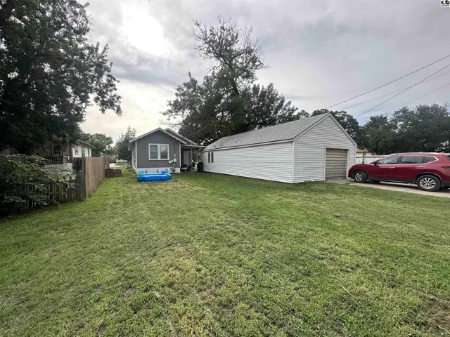 Spacious backyard with a detached garage, small blue pool, and a red SUV parked in the driveway.