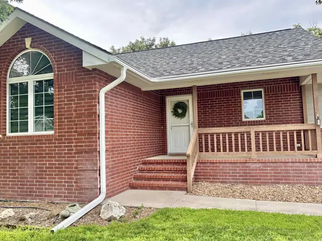 Red brick ranch home with a covered porch, arched window, and white trim.