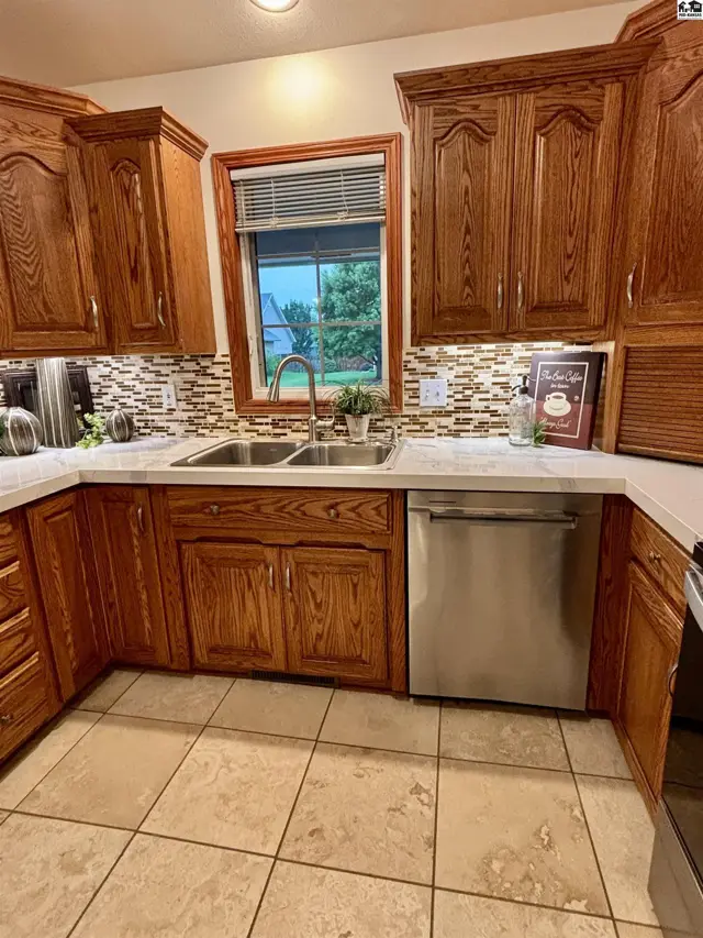 Kitchen with oak cabinets, granite countertops, stainless steel appliances, and tile backsplash.