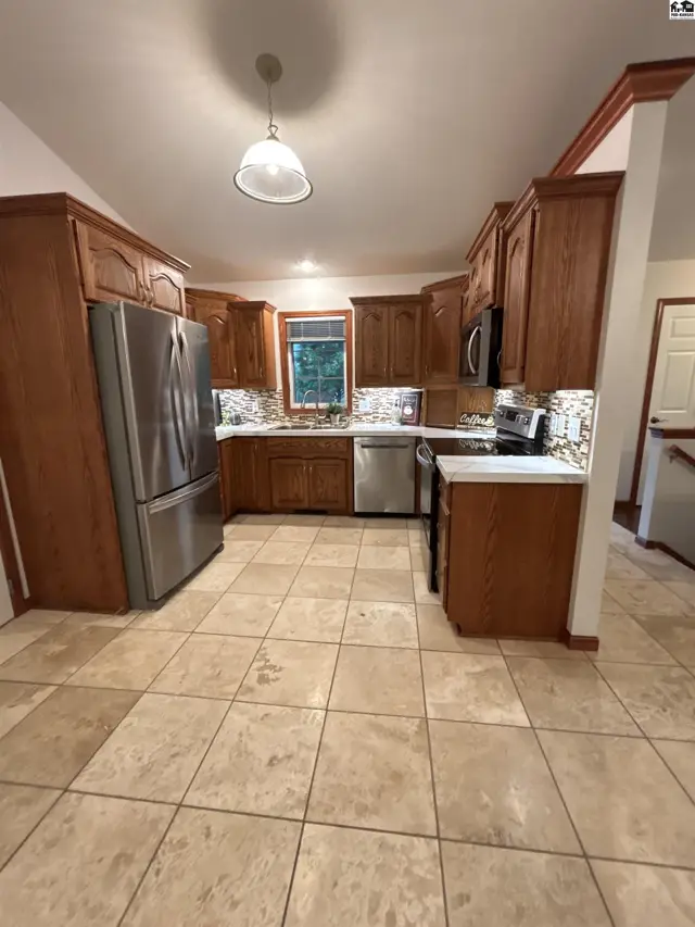 Spacious kitchen with warm oak cabinets, stainless steel appliances, and tiled floors.