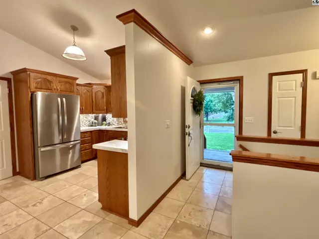 Spacious entryway with tiled floor, leading to a kitchen with oak cabinets and stainless steel appliances.