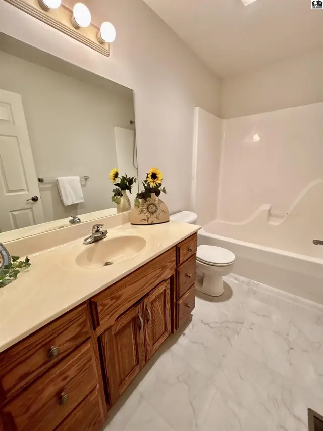 Spacious bathroom with a double vanity, white tub, and marble-look flooring.