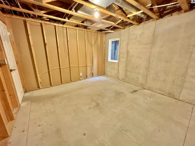 Unfinished basement room with concrete floor, exposed joists, and framed walls.