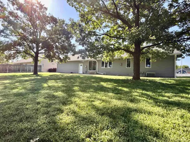This single-story home features a light gray exterior and a spacious, manicured lawn.