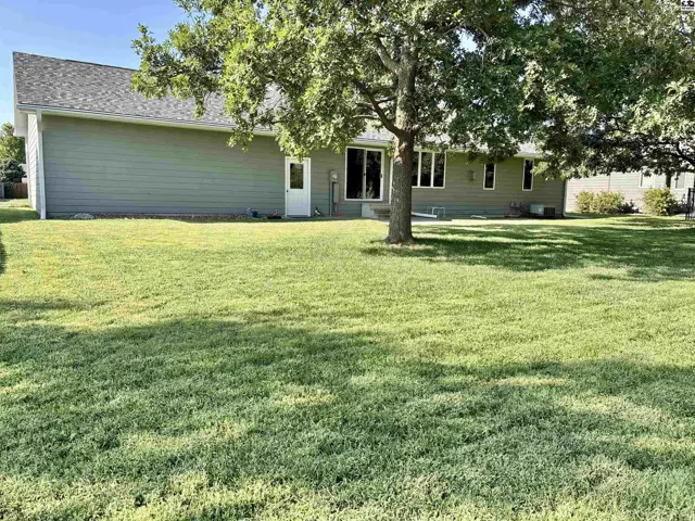 A light green home with a sliding glass door sits on a large, manicured lawn.