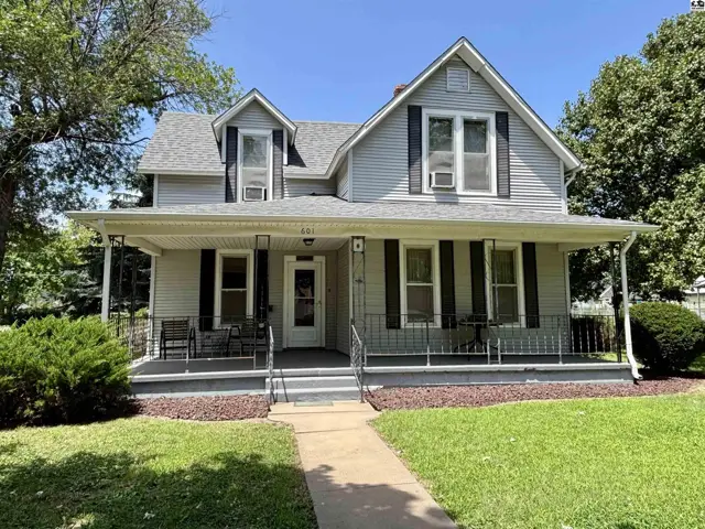 Light gray siding and black shutters adorn this charming two-story home with a wraparound porch.