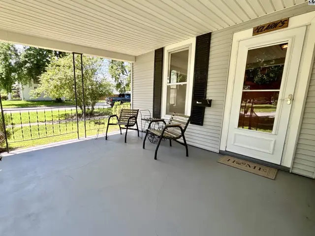 Covered front porch with seating, white door, and light gray painted floor.