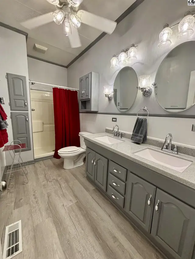 Spacious bathroom with a double vanity, gray cabinets, and a red shower curtain.
