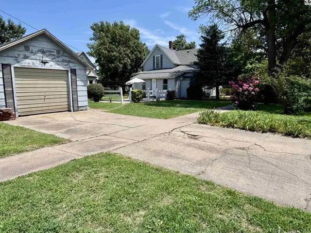 Light blue house with white trim and a detached garage on a sunny day.