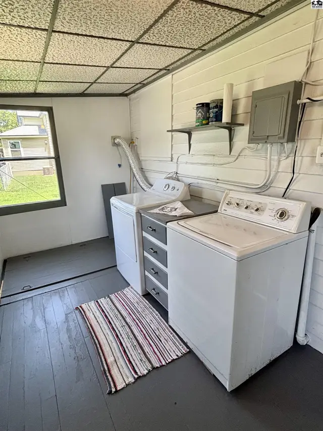 Laundry room with white washer and dryer, gray floor, and paneled walls.
