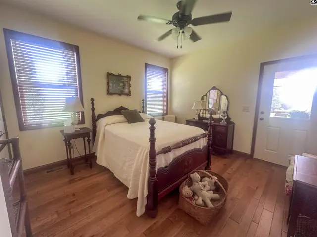 Bedroom with wood floors, very spacious closet, and exterior door to wraparound screen porch.
