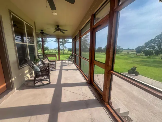 View of wraparound screened in porch with concrete floor and access to patio.