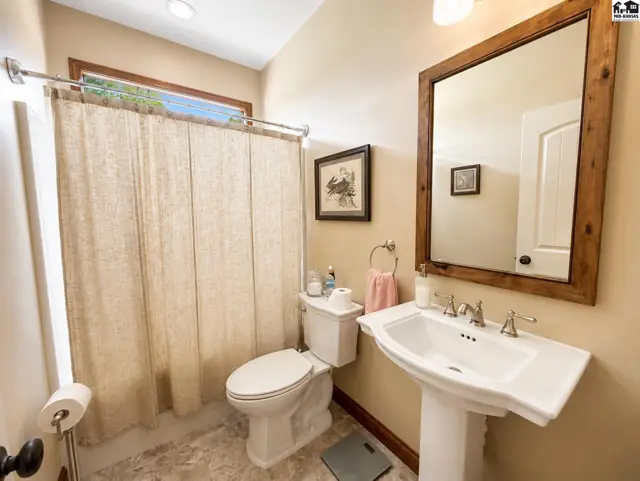 Main bathroom adjacent to guest bedrooms, offers transom window above tub/shower & custom mirror.