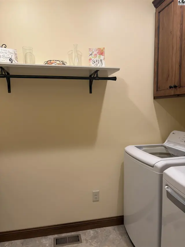 Laundry room offers onyx sink and custom cabinetry above washer/dryer.