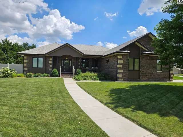 Spacious ranch home with brick and stone exterior, manicured lawn, and inviting walkway.