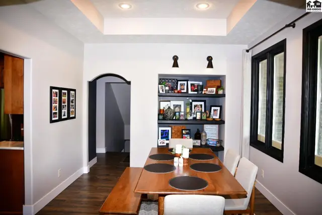 Dining room with wood table, built-in shelves, and tray ceiling.