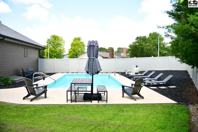 Spacious backyard with a sparkling swimming pool, lounge chairs, and outdoor seating.