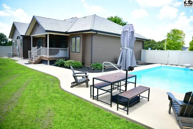 Spacious backyard features a swimming pool, patio furniture, and a well-maintained lawn.