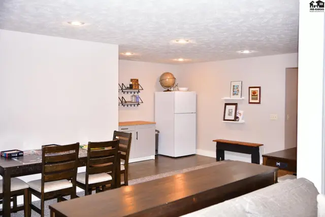 Spacious living area with dining table, white refrigerator, and decorative shelves.