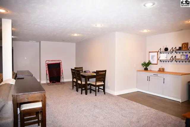 Spacious finished basement with dining set, bar, and built-in shelving.