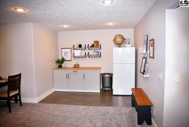 Modern basement living area with gray cabinets, butcher block countertop, and concrete floor.