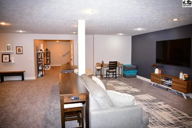 Spacious finished basement with a sectional sofa, dining area, and entertainment wall with a large TV.