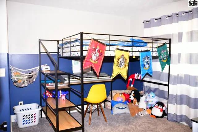 Loft bed with integrated desk and shelves, decorated with Harry Potter banners, in a blue and gray room.