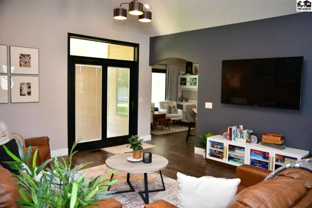 Spacious living room with vaulted ceiling, dark gray accent wall, leather furniture, and glass doors.